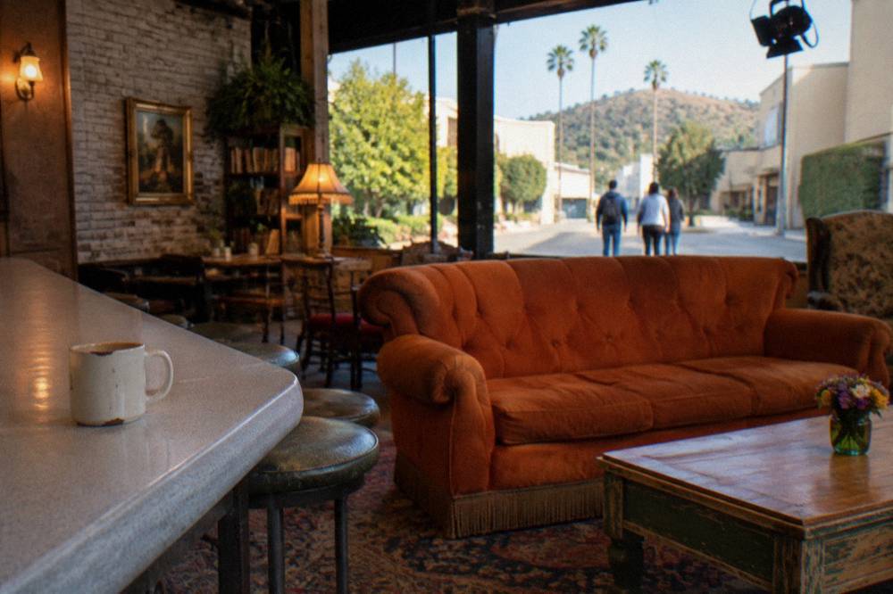 A recreated café set with an orange couch under studio lighting