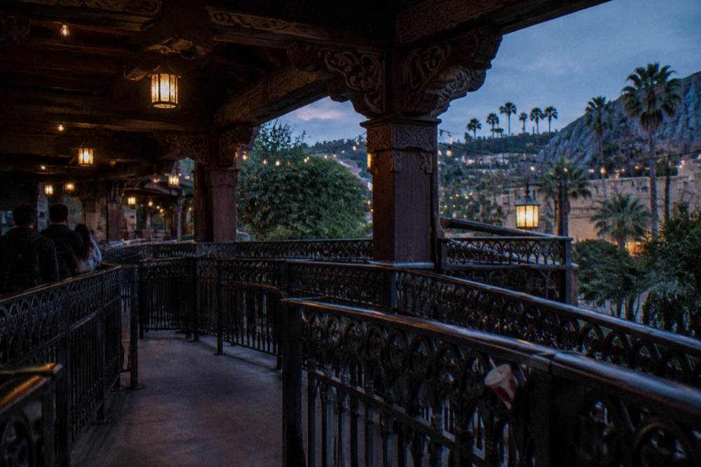 Ride queue switchbacks in shaded walkway with theme architecture overhead