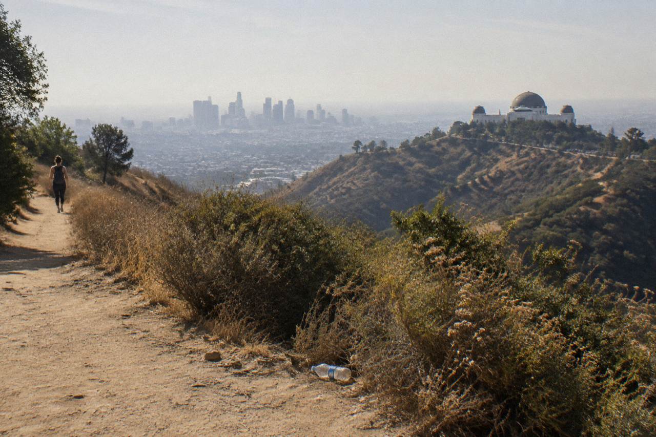 A distant view of the Hollywood Sign on the hillside with the Los Angeles skyline visible below.