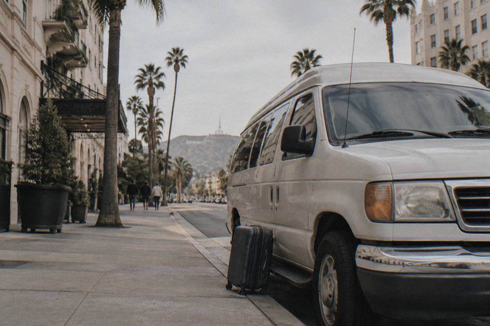 Tour van parked on a sunny Los Angeles street lined with palm trees