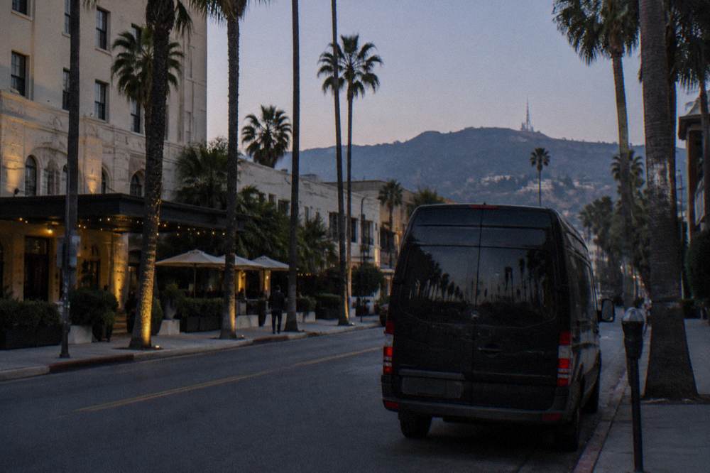 A tour van parked on a city street with hills in the distance