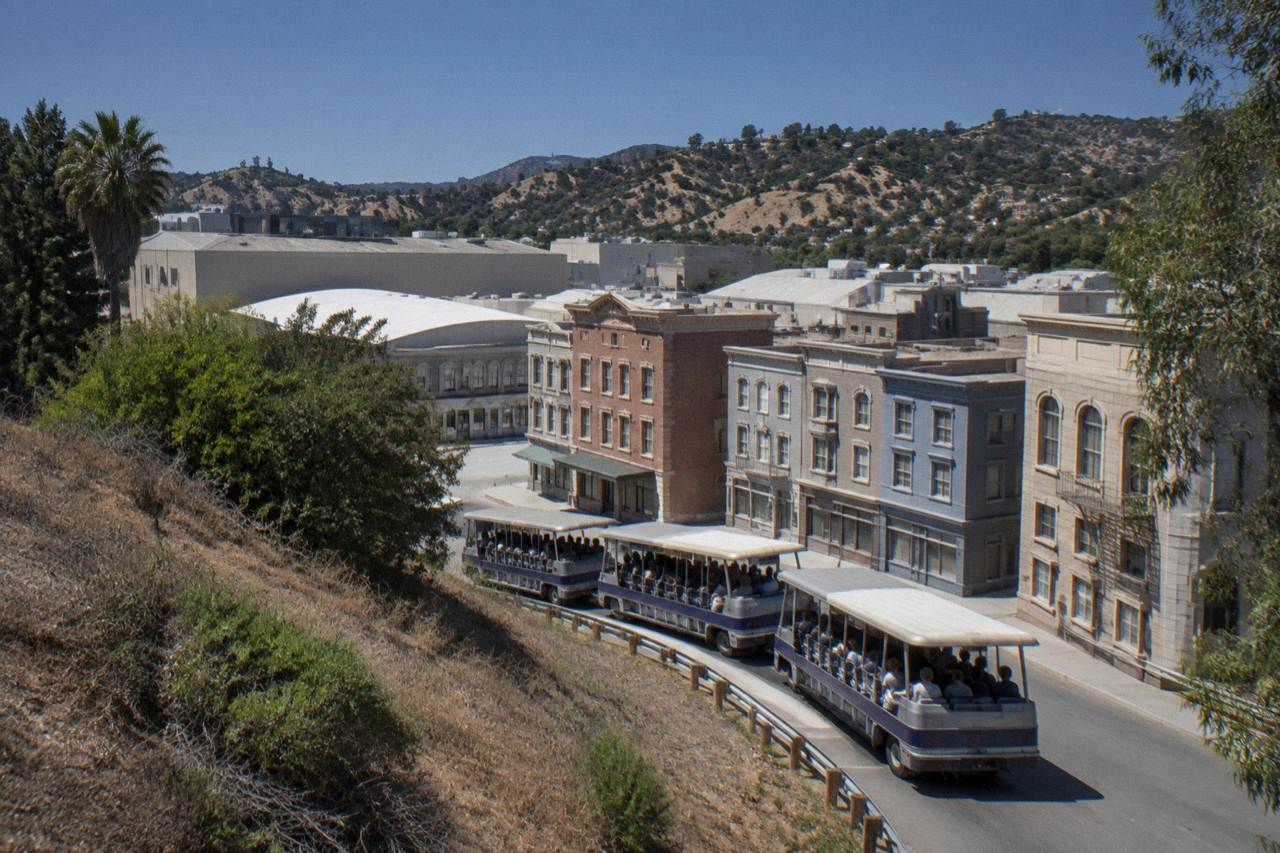 Studio tour tram winding past a facade row on the Universal City backlot under a clear sky