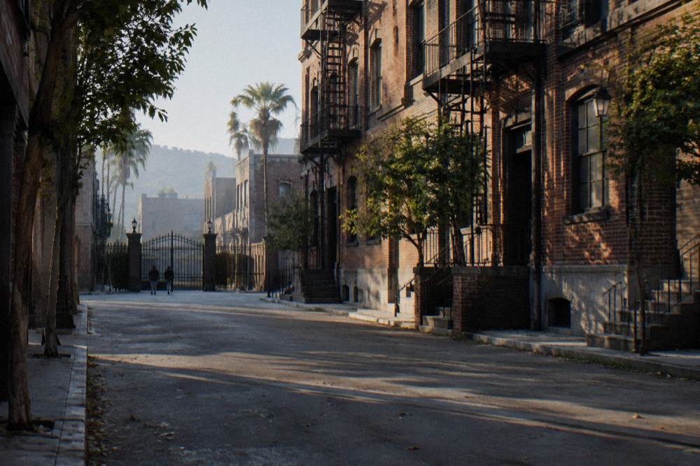 Paramount studio backlot street with brick facades and a wrought iron gate under morning light