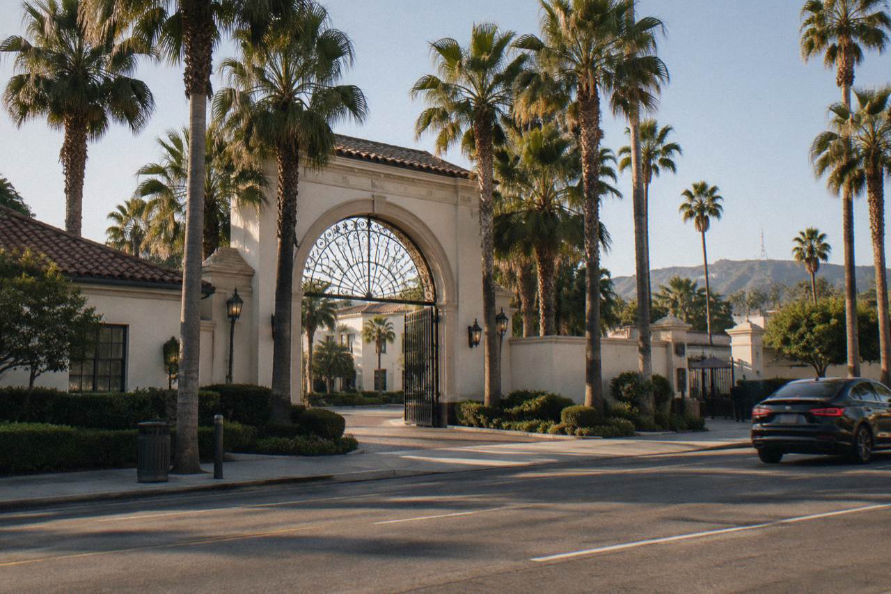 A street sign for Melrose Avenue with the Paramount Pictures gate visible in the background on a sunny day