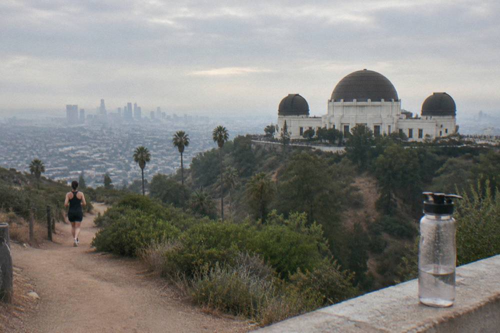A hillside trail above Los Angeles with the city spread out below under morning haze