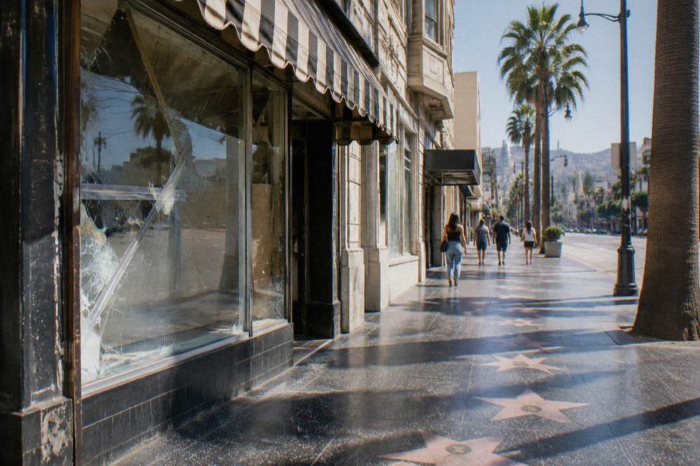A vintage Los Angeles storefront facade with neon signage and a marquee-style awning along a sunny sidewalk
