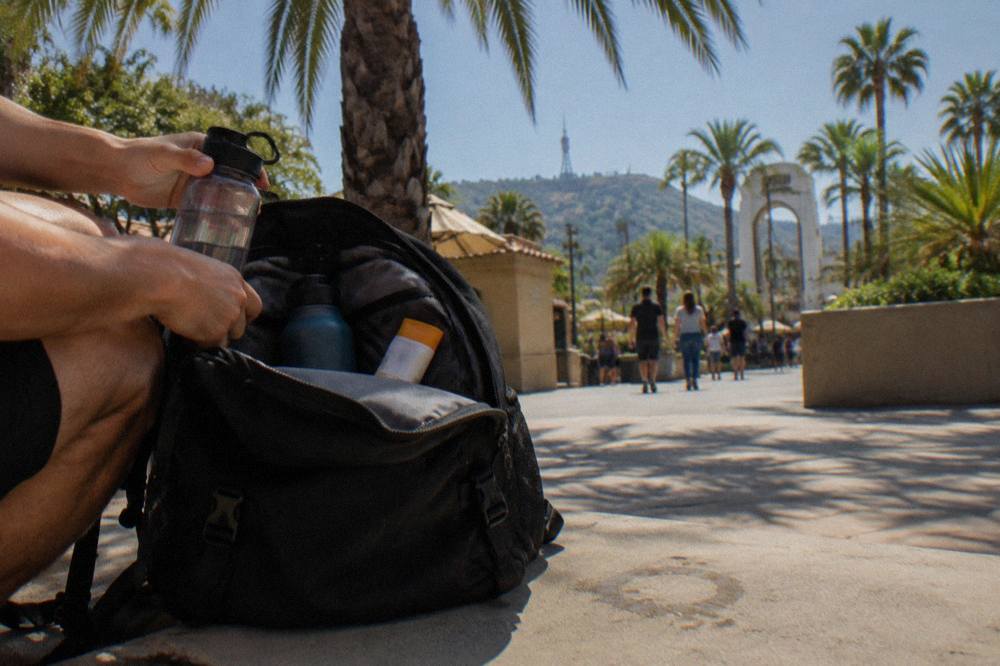 Open backpack on a bench with water bottles and sunscreen being packed for a park day