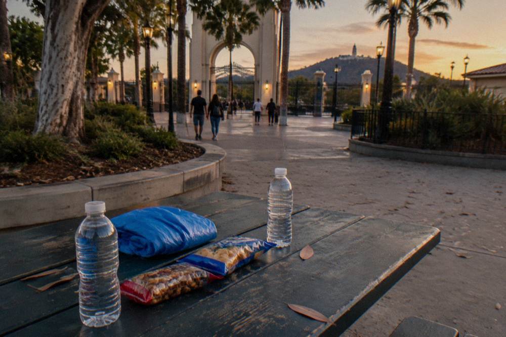 Water bottles and sealed snack packages arranged beside a folded poncho on a table