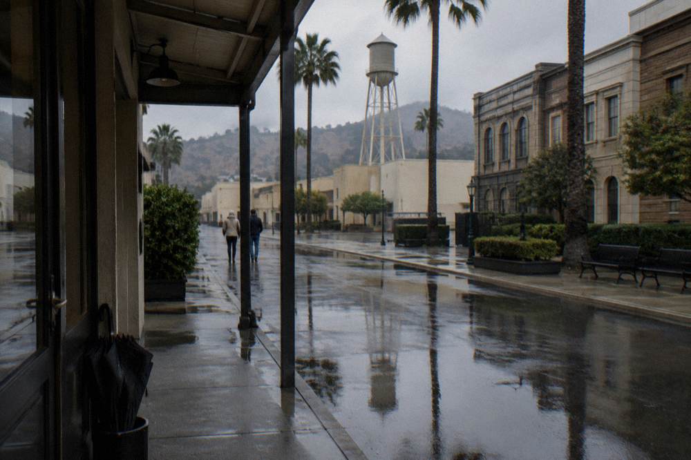 Guests in casual clothes and light jackets walking past studio facades
