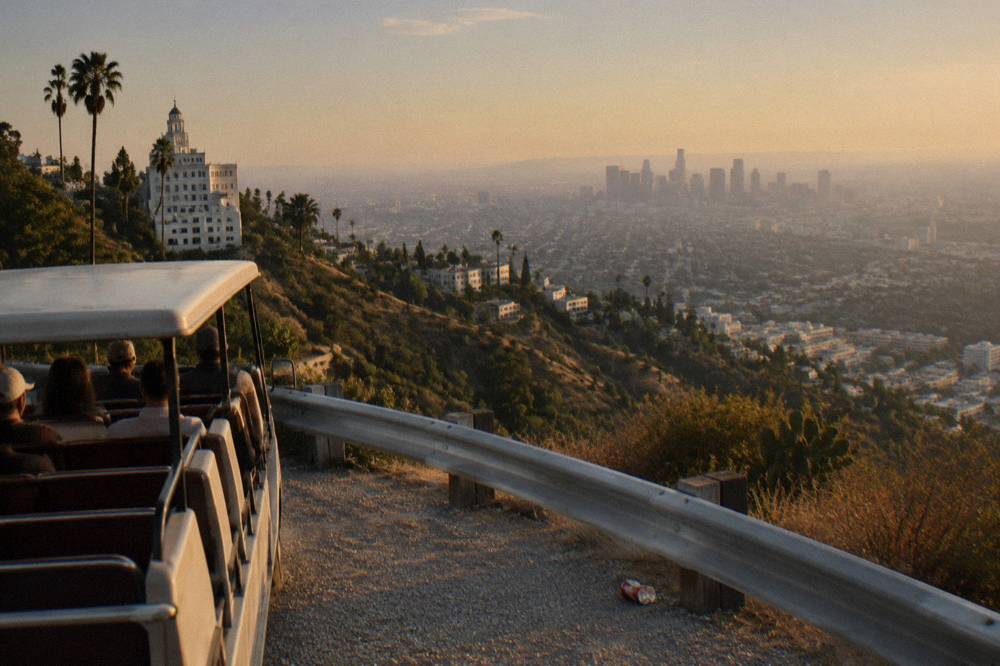 An open-air tour vehicle on a canyon road with the Los Angeles basin below