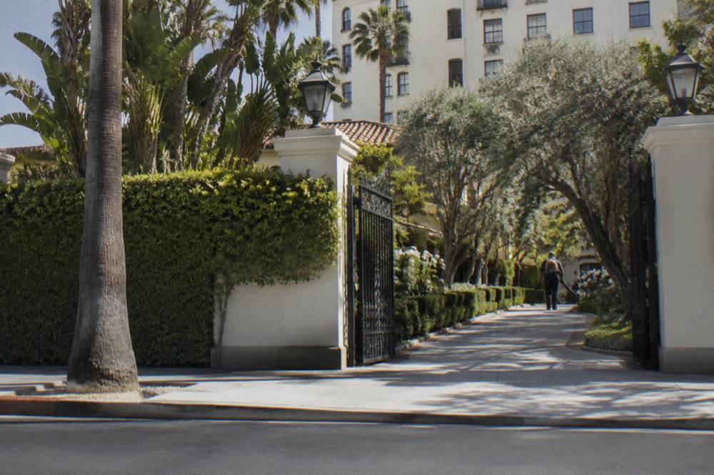 A gated estate driveway with manicured hedges seen from the street