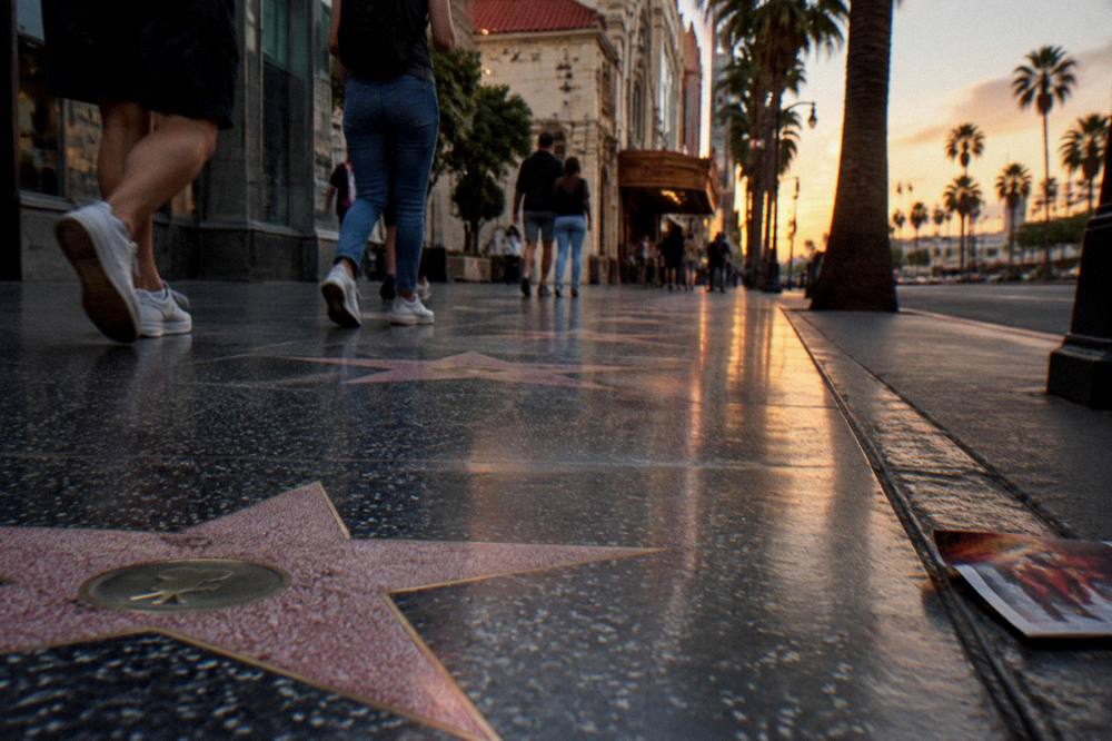The Hollywood Walk of Fame sidewalk with terrazzo stars stretching toward a theater facade