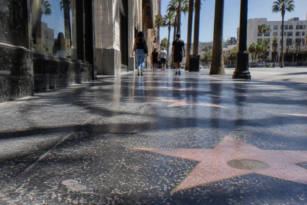 Wide sidewalk lined with pink terrazzo stars and bronze names inlaid into the concrete