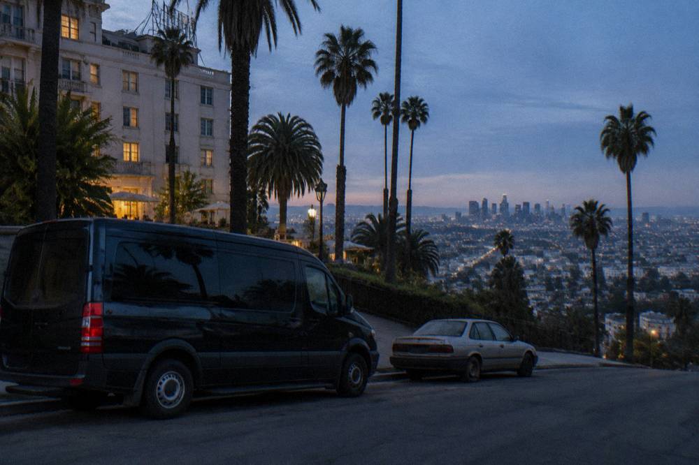 A private passenger van parked on a residential hillside street overlooking the city