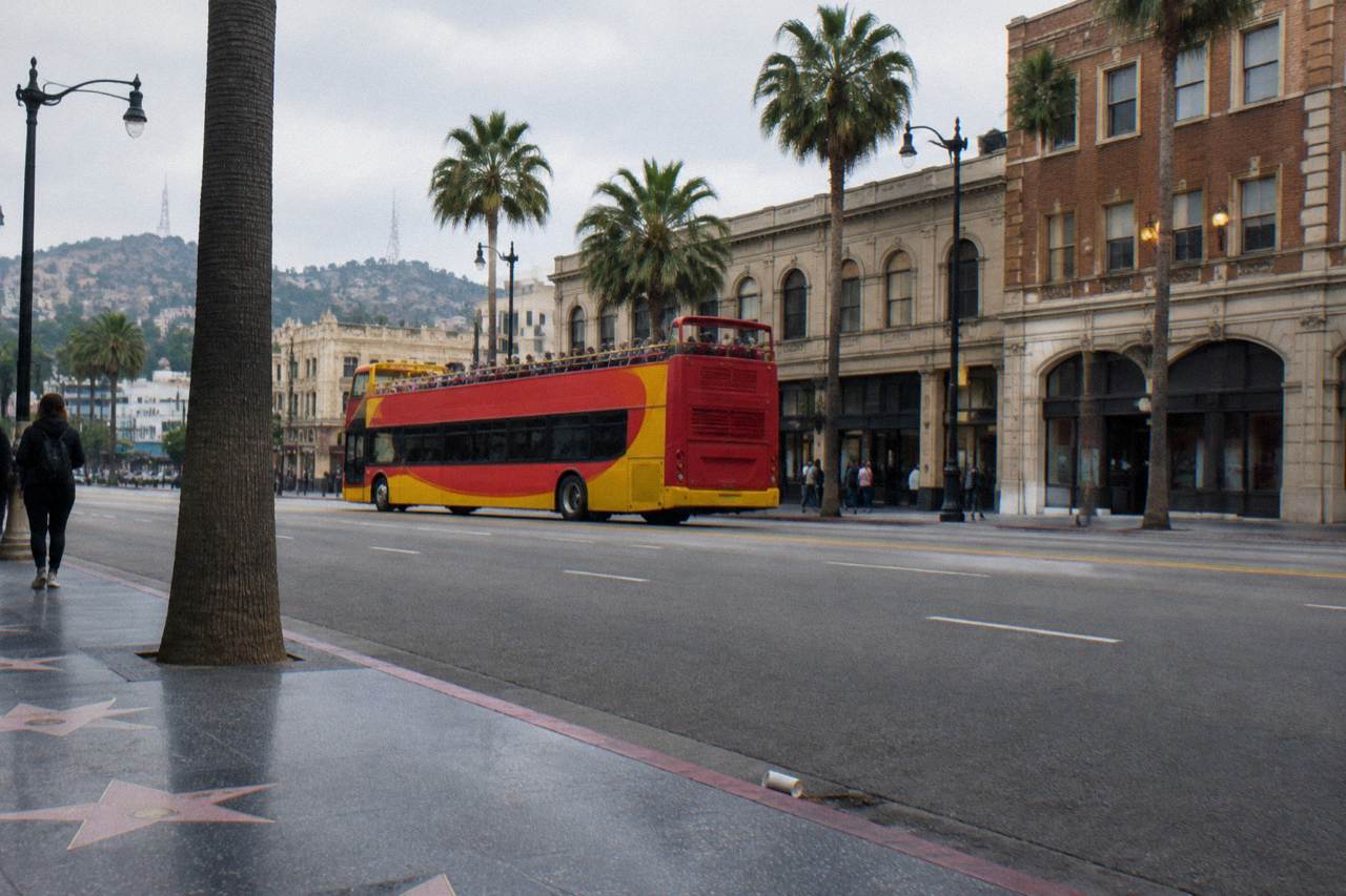 An open-top tour bus on Hollywood Boulevard with the Hollywood Hills in the background
