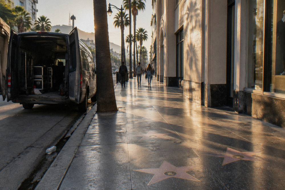 An open touring van parked on a sunny Hollywood Boulevard lined with palm trees