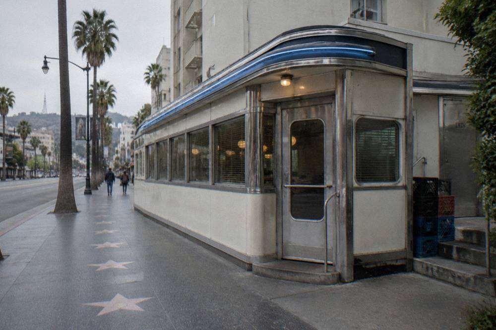 A classic 1930s diner storefront with neon signage on a quiet Los Angeles street