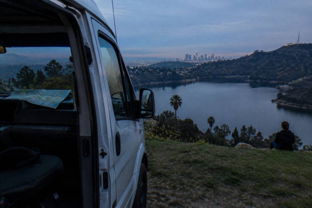 A tour van parked at a Hollywood Hills overlook with the city spread out below