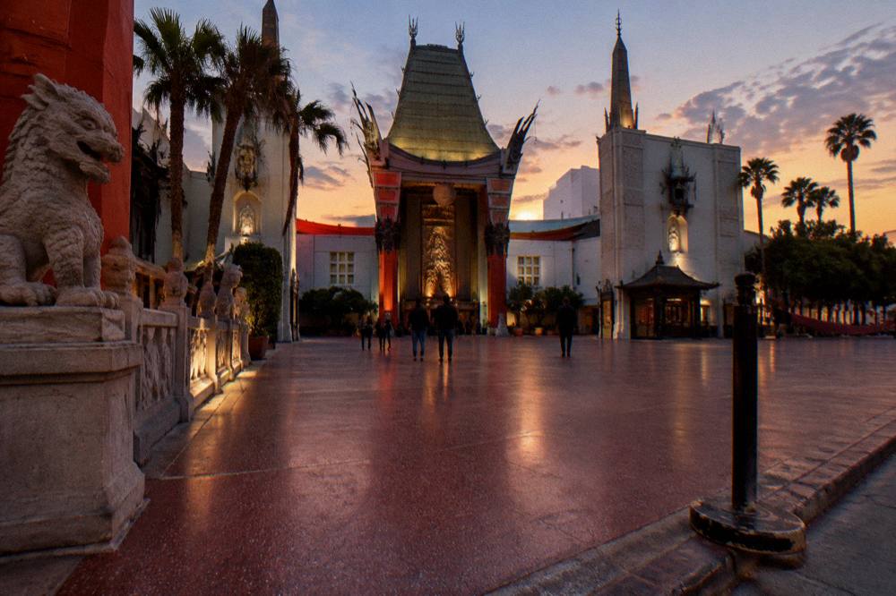 A classic Hollywood storefront with neon signage along a boulevard at golden hour