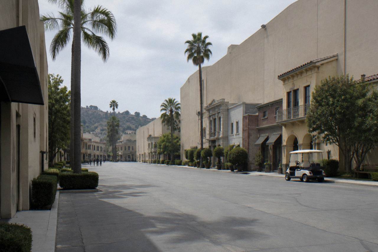 Studio backlot street with soundstage facades under a clear Los Angeles sky