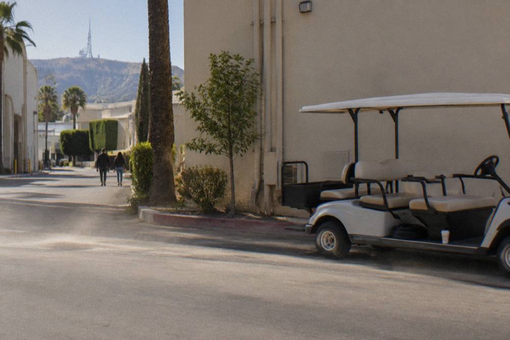 Studio tour cart parked beside a soundstage facade on a working film lot