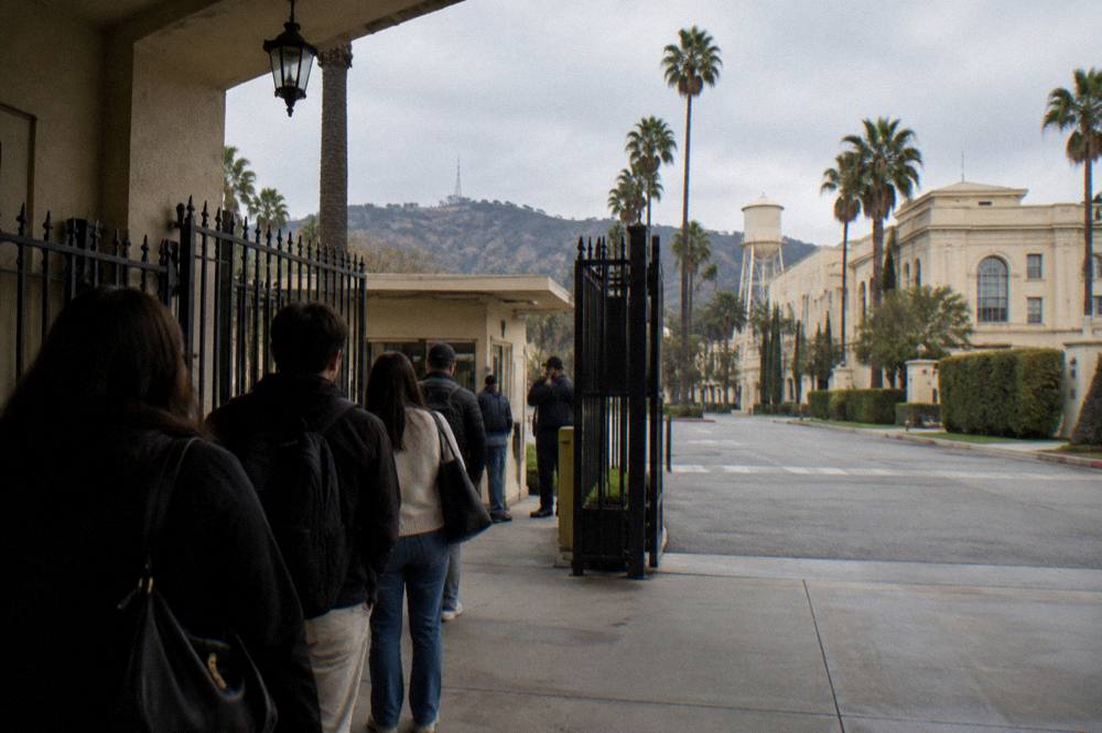 Security gate and walkway at a studio entrance with visitors waiting in a short line