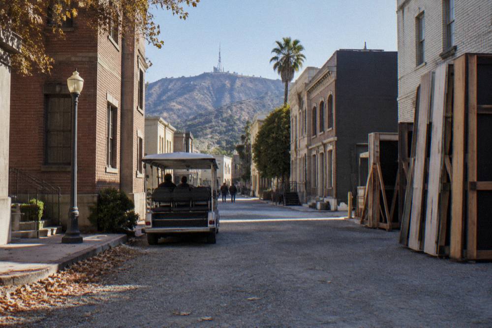 Guided tour cart parked on a studio backlot street lined with facade buildings