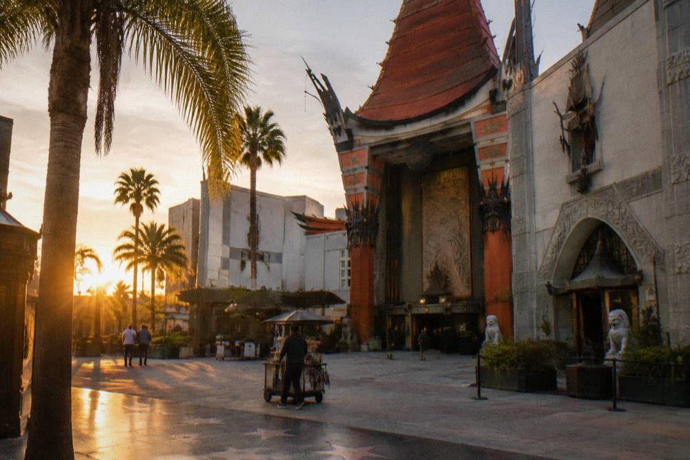 Historic theatre facade on Hollywood Boulevard at golden hour with palm trees