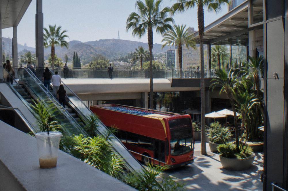Open-air tour bus on a Hollywood street with hills in the background