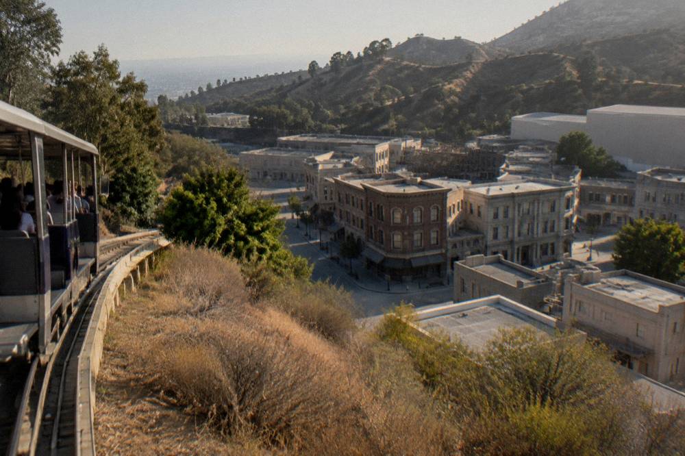 Theme park hillside with a tram track winding past backlot buildings