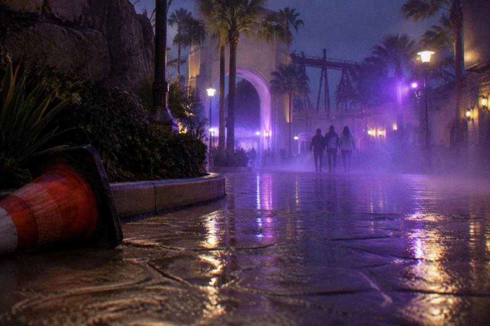 A park plaza at night with fog machines and purple event lighting along a walkway