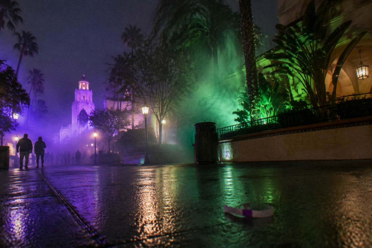 Fog and purple light filling a themed event street at a theme park at night