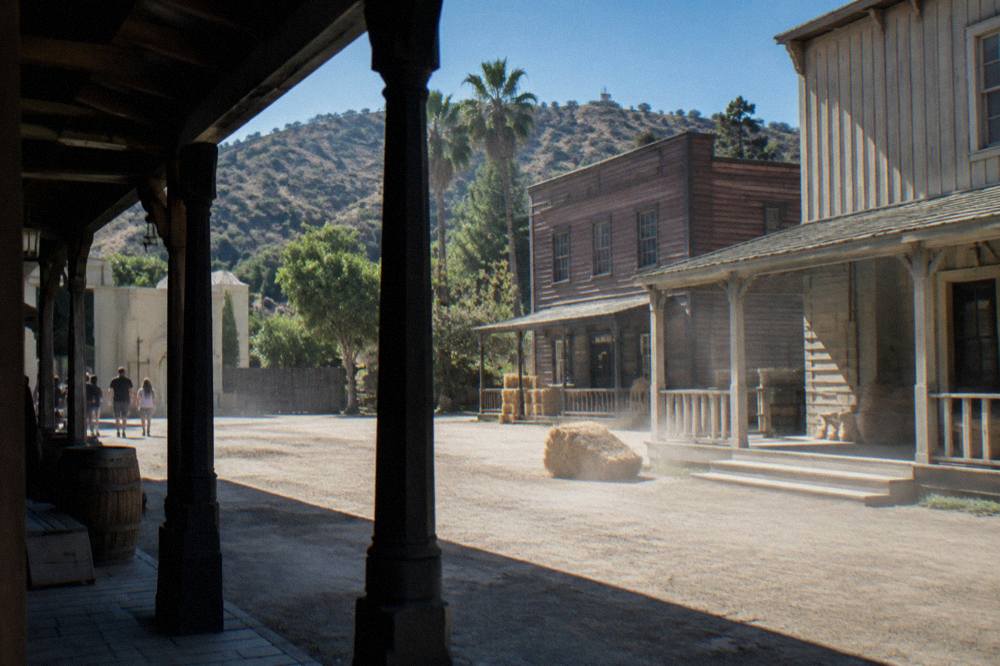 Theme park backlot street with facades of town buildings under a clear sky
