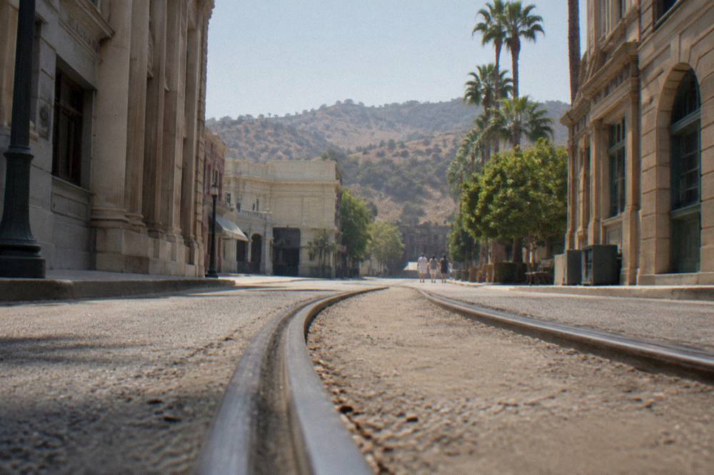 Studio backlot street with movie facades and a tram track curving between buildings