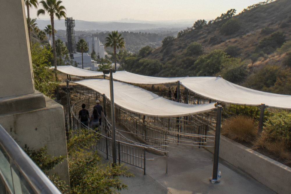 Tram queue canopy inside a theme park with hills behind