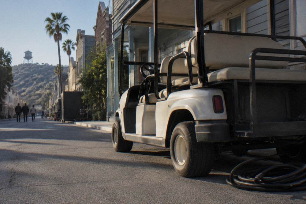 Golf-style tour cart parked on a sunny studio backlot street