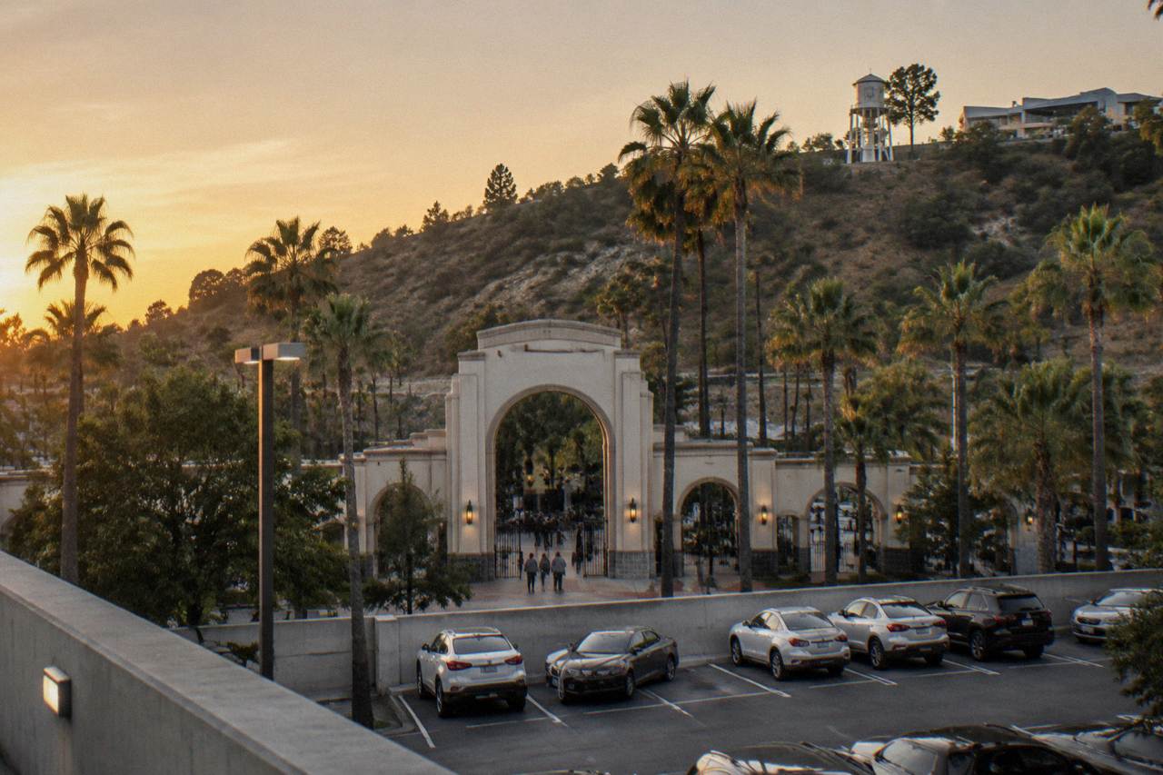 Entrance archway to a theme park on a hillside above a parking structure