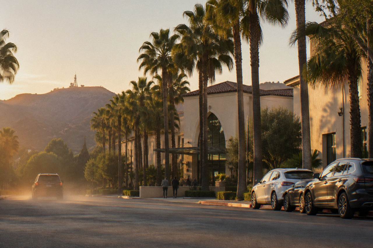 Entrance driveway of a studio tour welcome center in Burbank with parked cars and palm trees