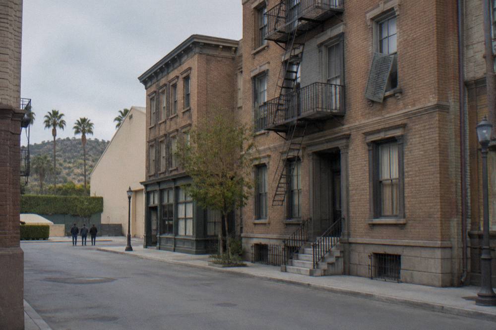A studio backlot street with brownstone facades under a clear sky